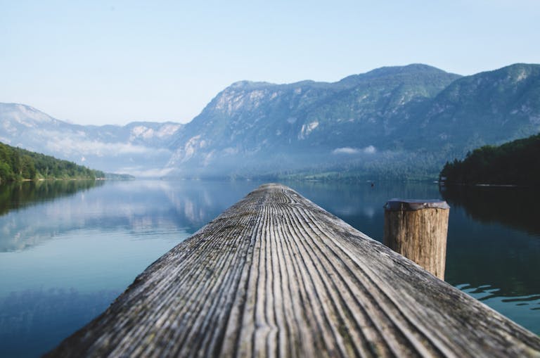 Serene view of a mountain lake from a wooden dock in Radovljica, Slovenia.